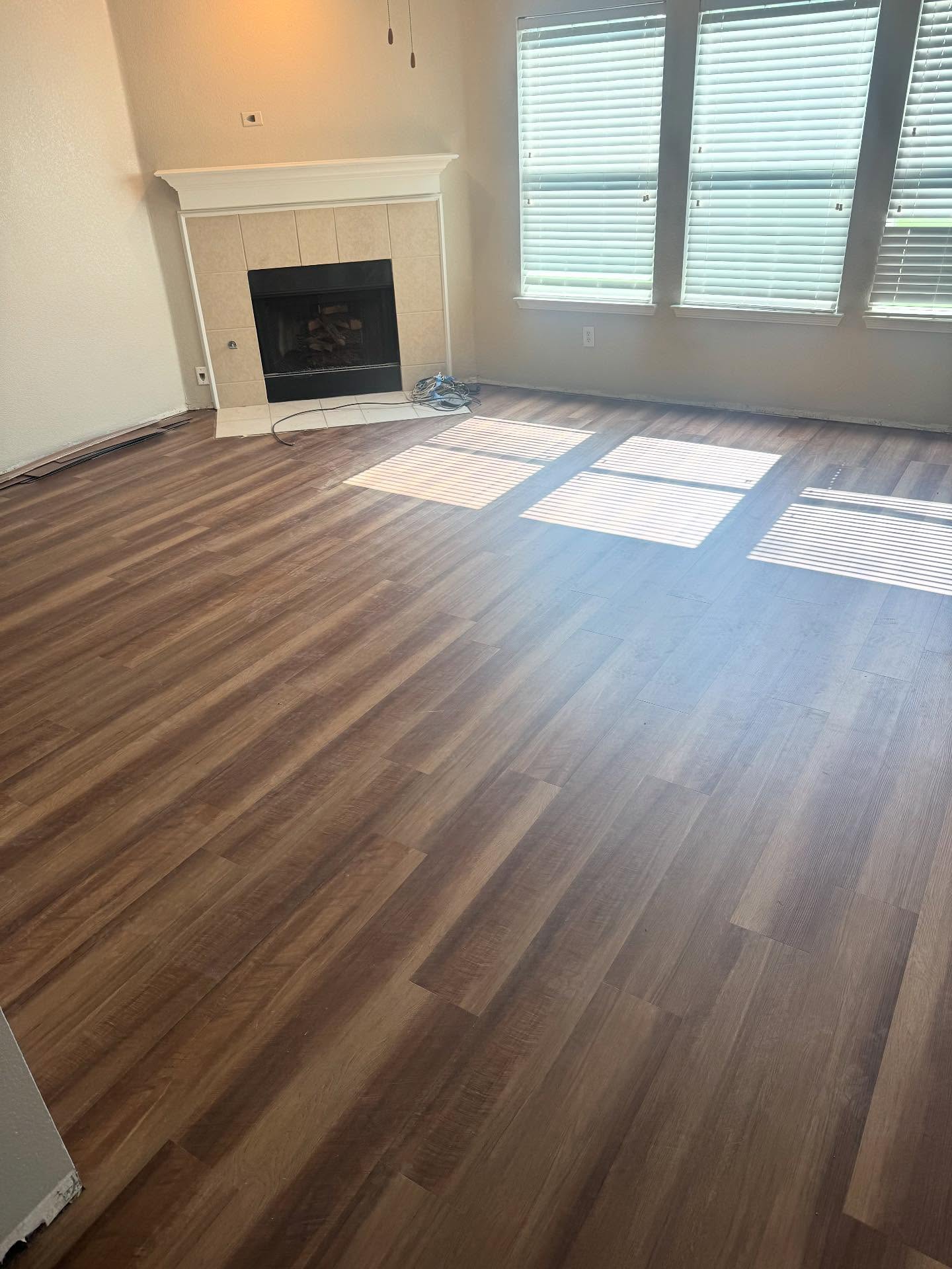 Luxury vinyl plank flooring installed in a bright living room with fireplace