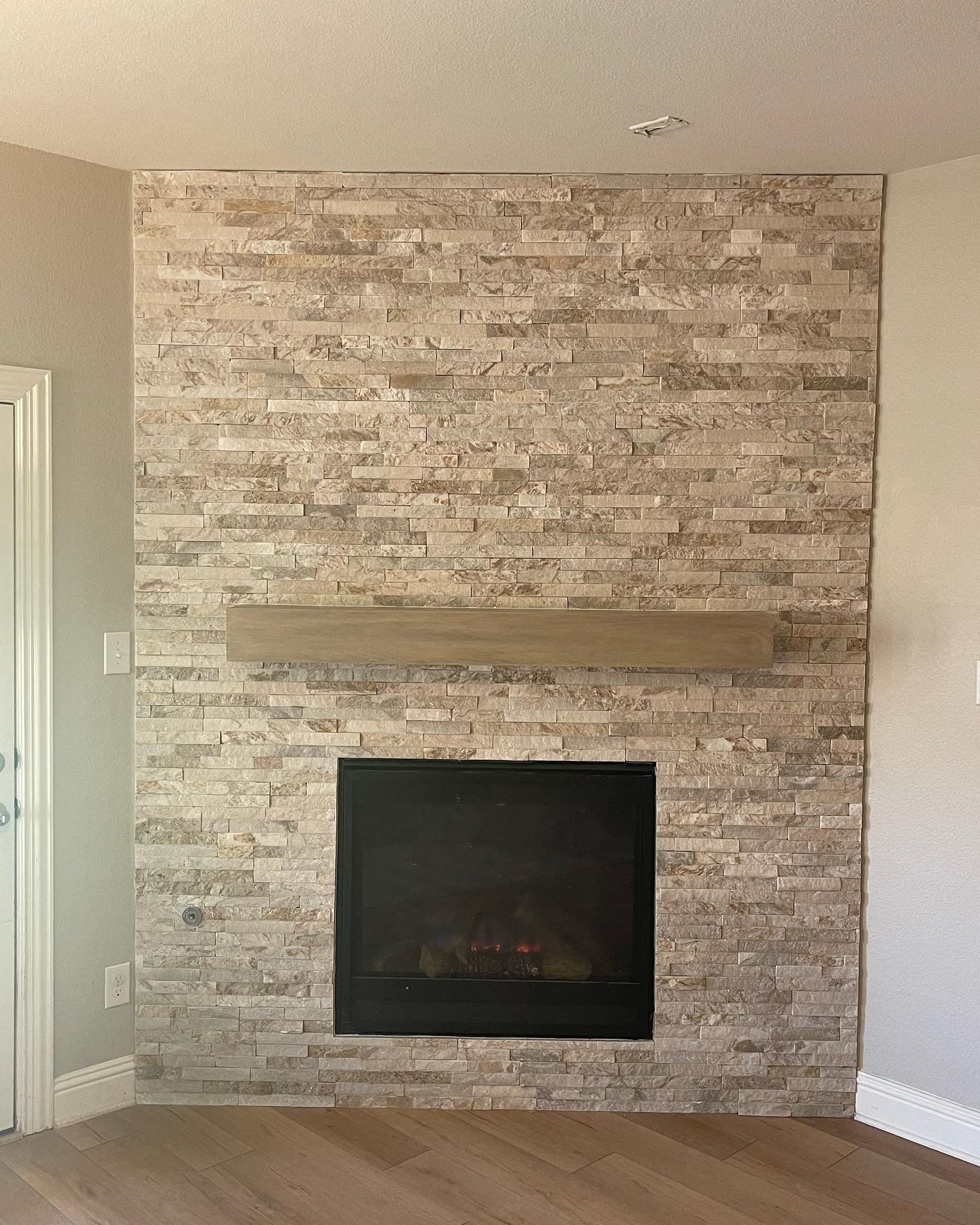 Stacked stone fireplace surround with floating wood mantel